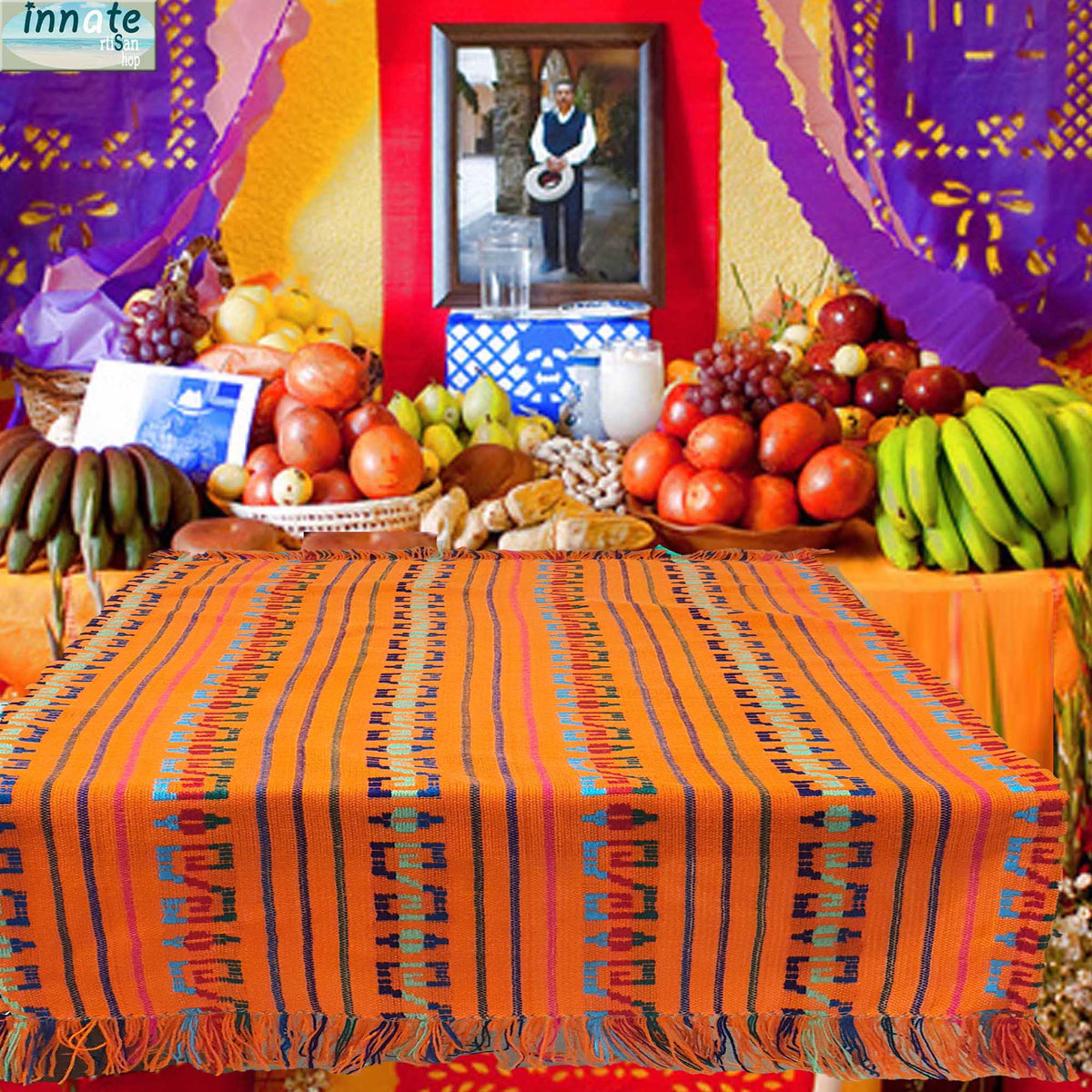 Colorful table setting with fruits and a patterned cloth, featuring a traditional portrait in the background.