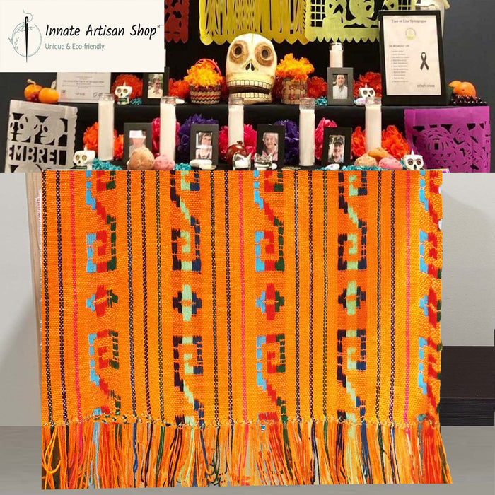 Decorative table with colorful patterned cloth, skulls, and other items on a gray background.