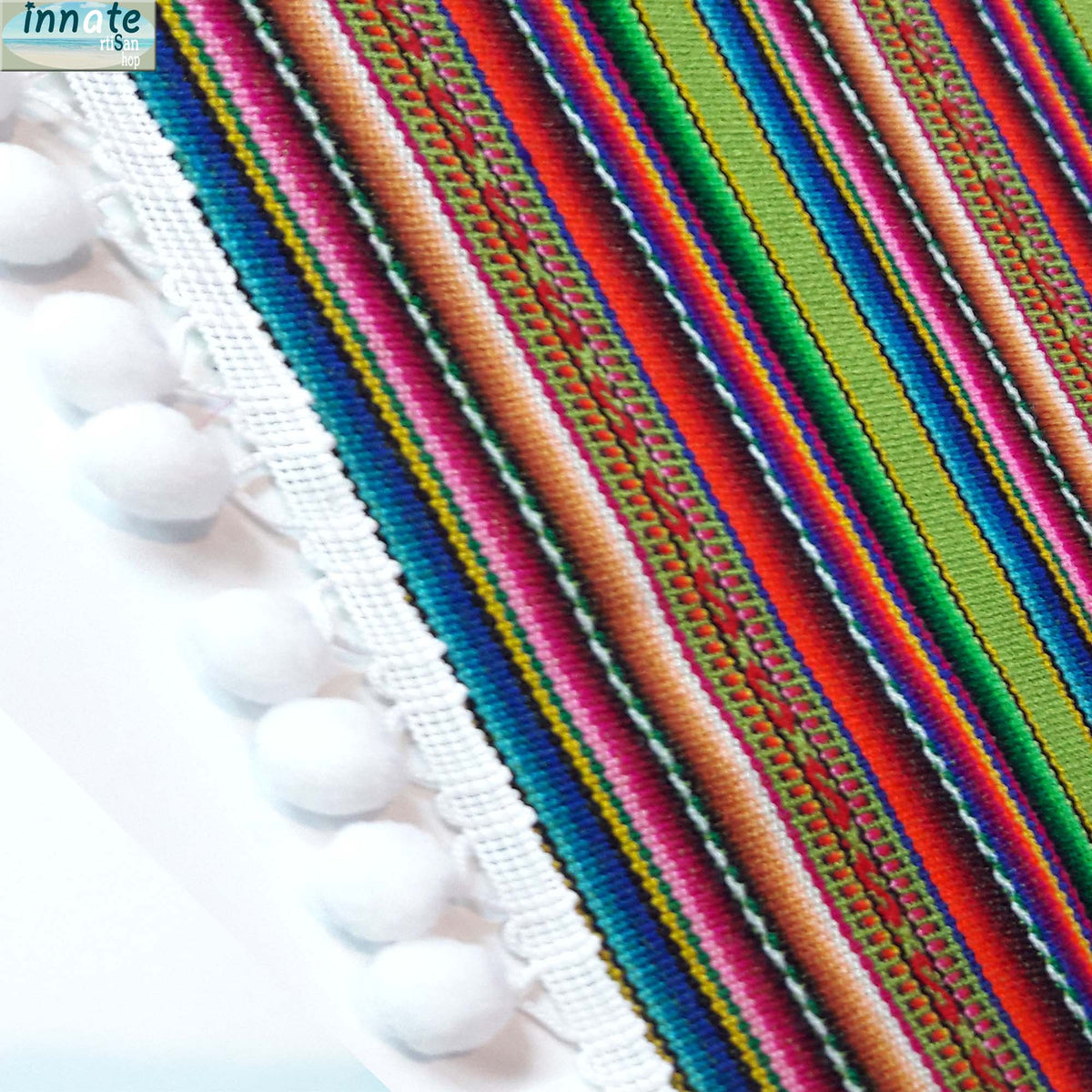 Colorful striped fabric with white tassels on a light background