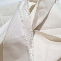 Close-up of beige fabric with frayed edge