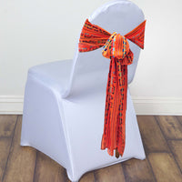 White chair with an orange and black patterned sash on a wooden floor.