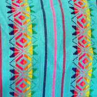 A close-up of a woven textile with a turquoise base and vertical geometric stripes in pink, red, yellow, green, and dark blue.