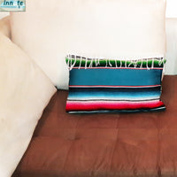 Colorful striped pillow on a brown couch with a beige wall in the background