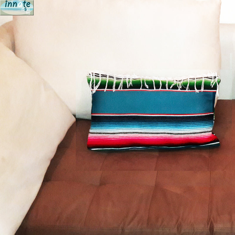 Colorful striped pillow on a brown couch with a beige wall in the background