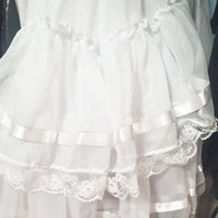 White lace-trimmed dress with ribbons on a dark background