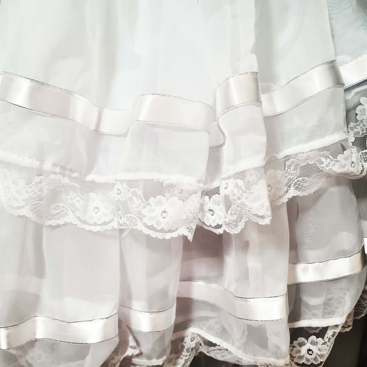 Close-up of a white lace-trimmed fabric with ribbons
