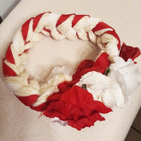 Red and white braided headband with flowers on a beige surface