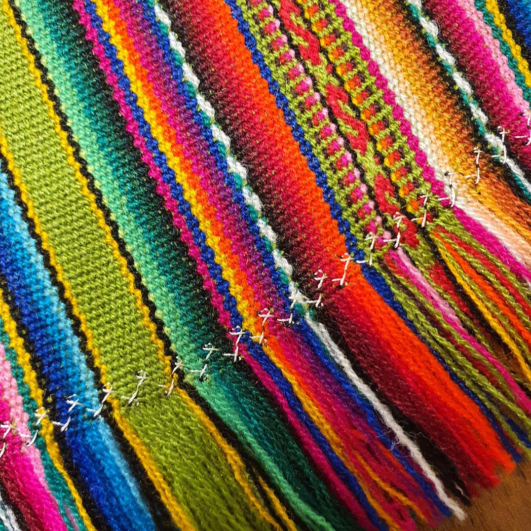Close-up of colorful woven fabric with a wooden surface underneath