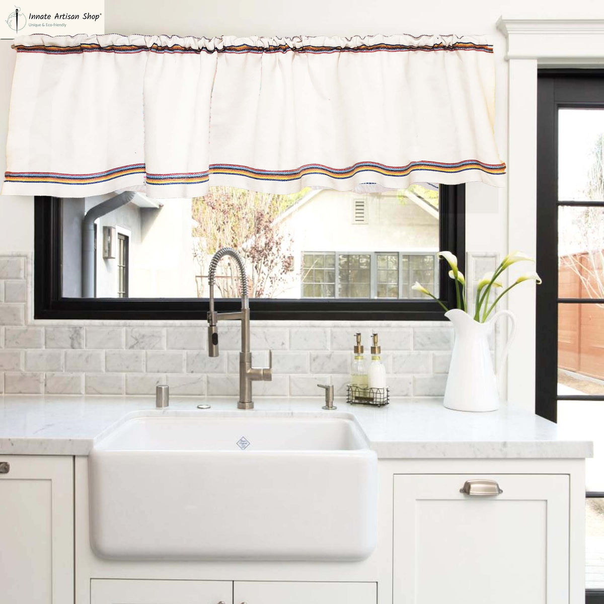 Kitchen with white sink, faucet, and window with decorative valance.