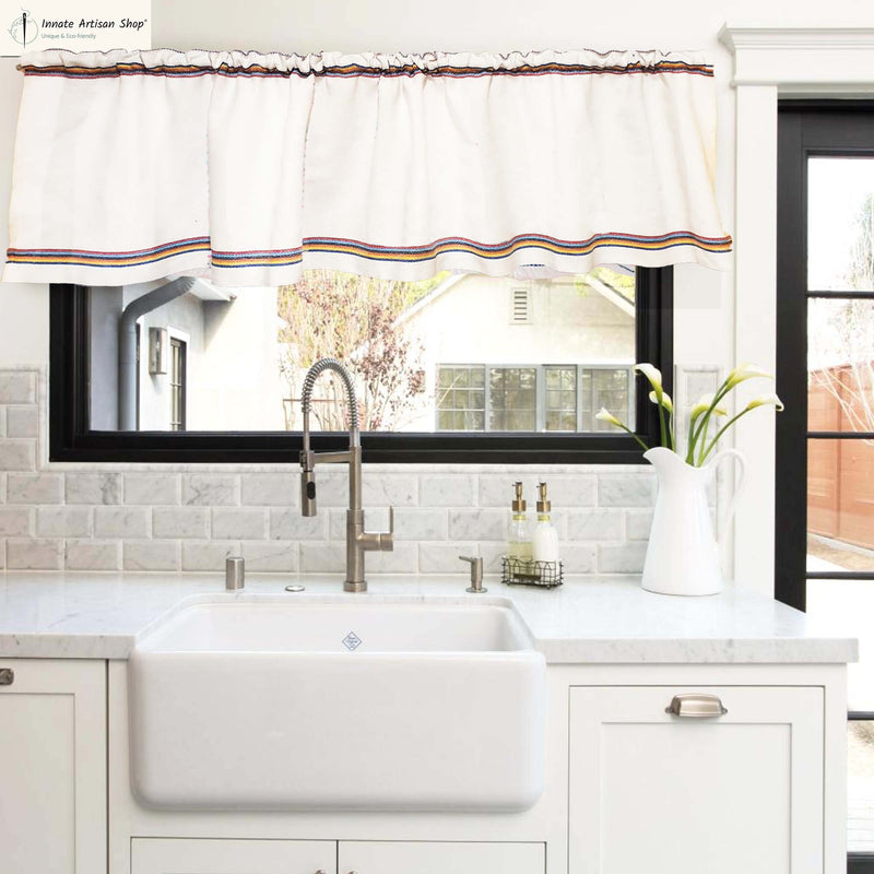 Kitchen with white sink, faucet, and window with decorative valance.