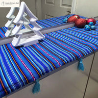 Blue striped tablecloth with decorative items on a table, featuring a white ironing board cover.