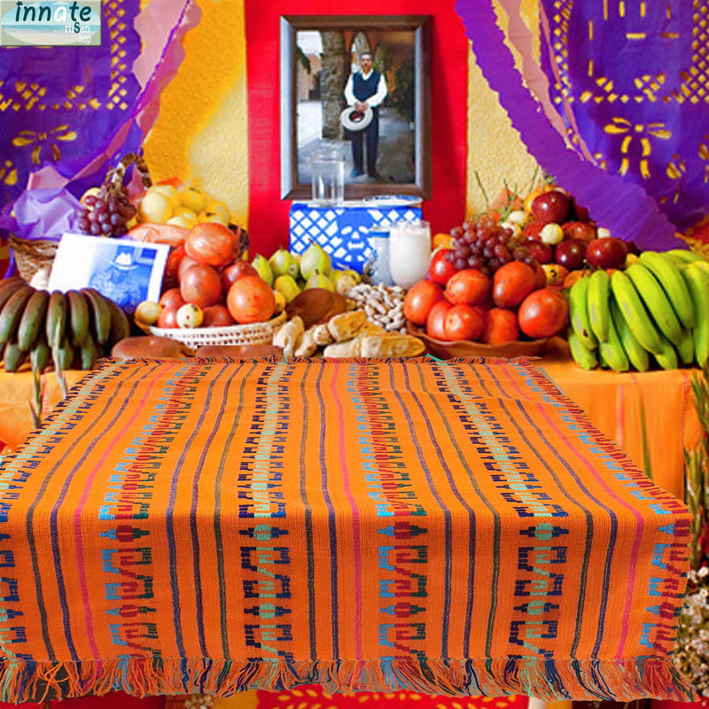 Colorful table setting with fruits and a patterned cloth, featuring a traditional portrait in the background.