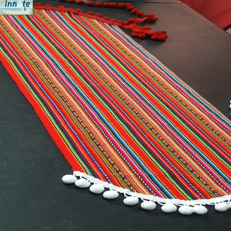 Colorful striped table runner with tassels on a dark surface