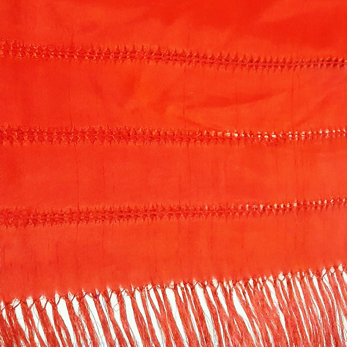 Close-up of a red fabric with white fringe