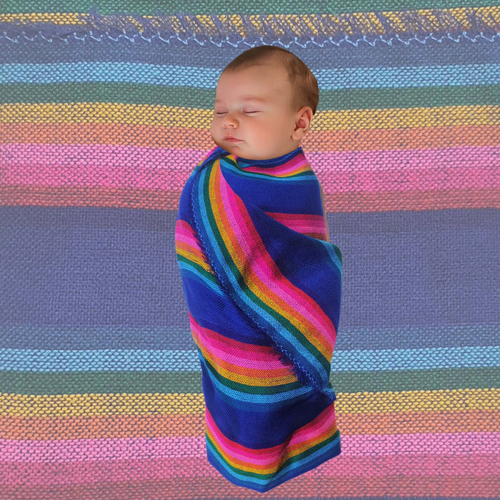 Baby wrapped in a colorful striped blanket against a striped fabric background