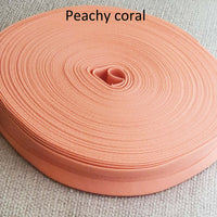 Roll of peachy coral fabric on a textured beige background