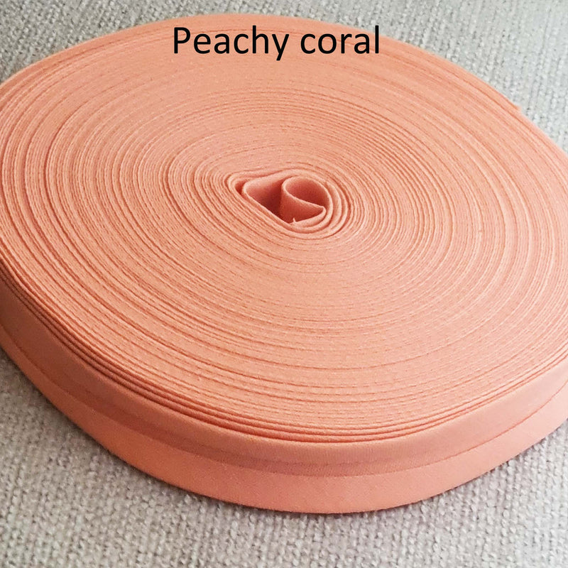Roll of peachy coral fabric on a textured beige background