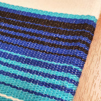 White serape on table, table runner, white and blue, artisan, close up of the woven