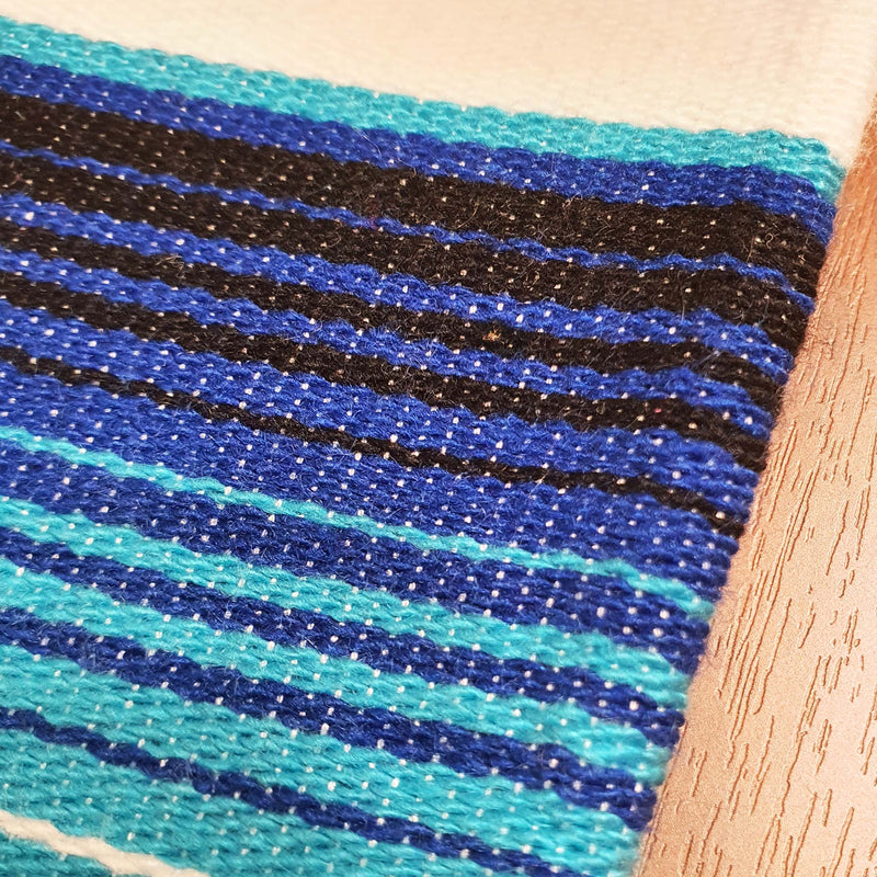 White serape on table, table runner, white and blue, artisan, close up of the woven