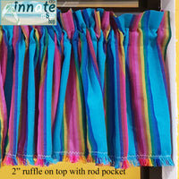 A close-up of a colorful striped fabric valance with vertical bands of turquoise, pink, purple, blue, yellow, and green, finished with fringe tassels and a top rod pocket. A logo for Innate Fabric Shop appears in the top-left corner, and a text overlay at the bottom reads '2" ruffle on top with rod pocket'.