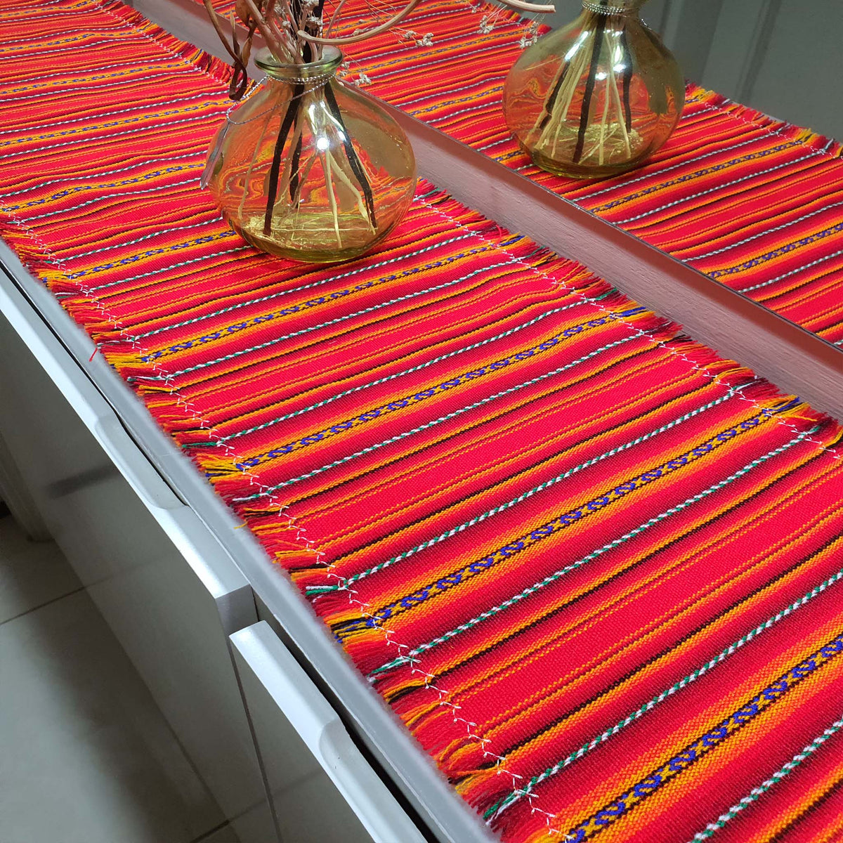Colorful striped table runner on a table with decorative vases.