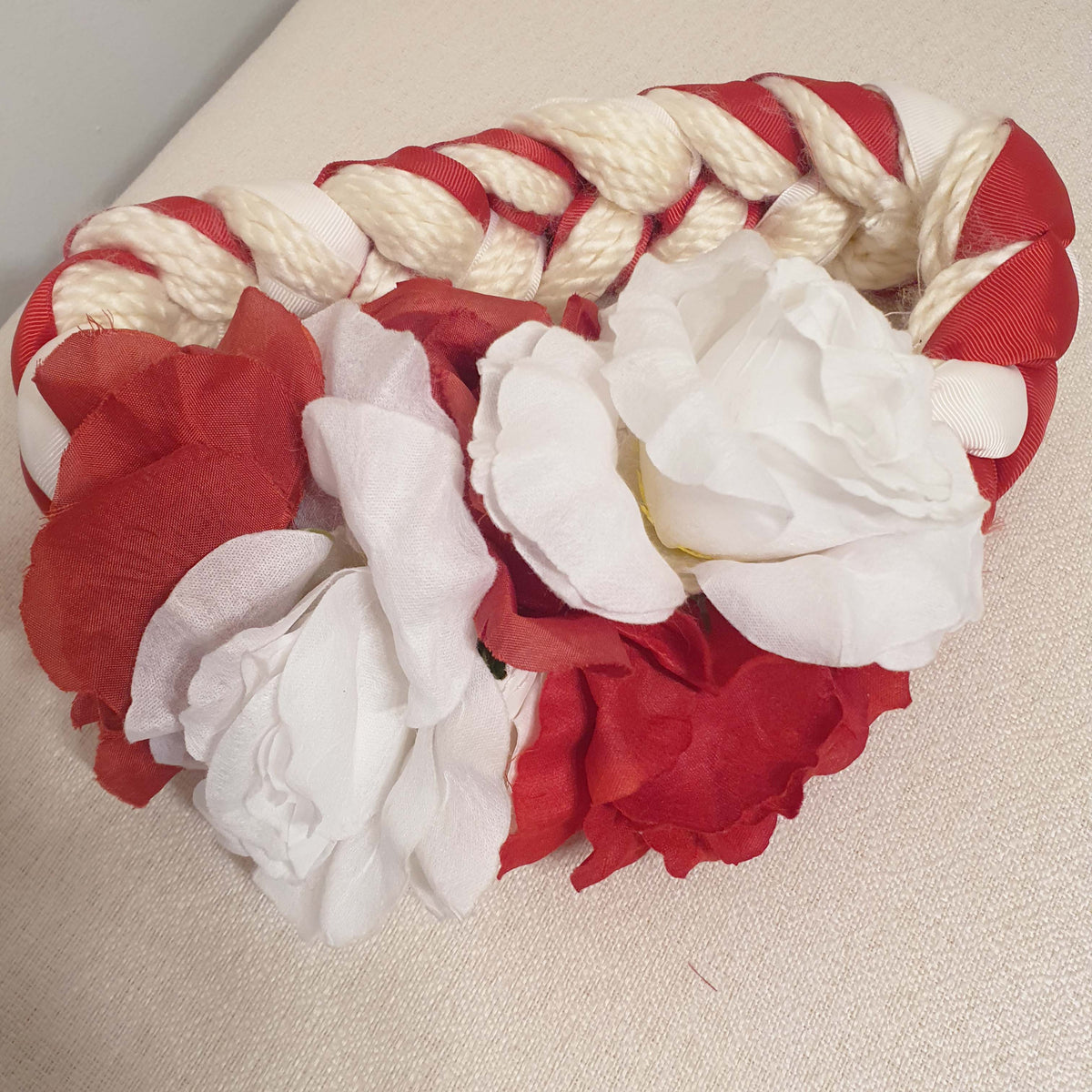 Red and white dog toy with rope on a beige surface