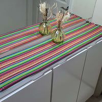 Colorful striped table runner on a kitchen counter with decorative vases.