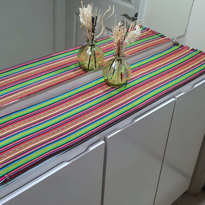 Colorful striped table runner on a kitchen counter with decorative vases.