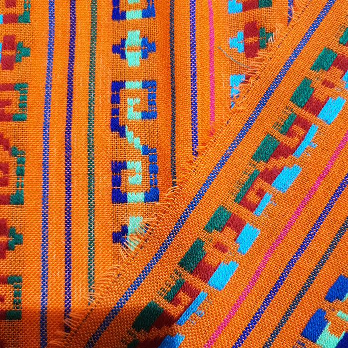 Close-up of colorful woven fabric with geometric patterns on an orange background