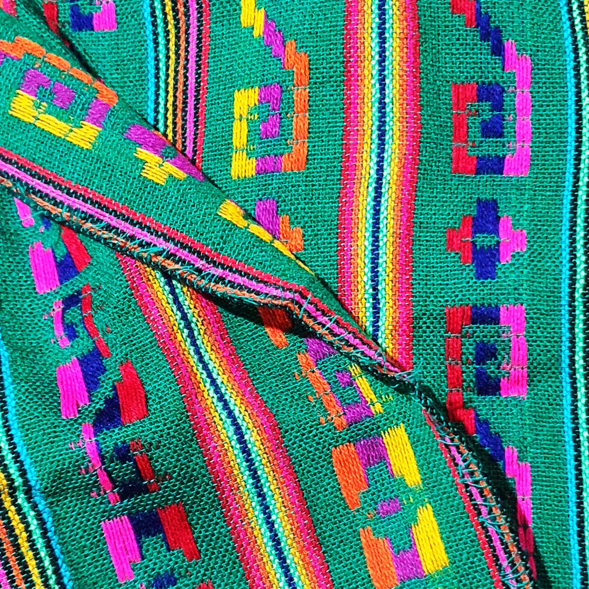 Close-up of a colorful woven fabric with geometric patterns on a teal background.