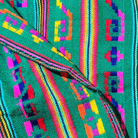 Close-up of a colorful woven fabric with geometric patterns on a teal background.