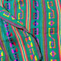 Colorful woven fabric with geometric patterns on a green background