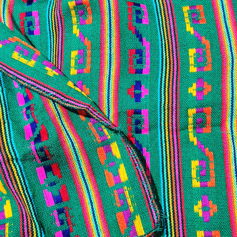 Colorful woven fabric with geometric patterns on a green background