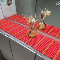 Orange striped table runner with gold vases and decorative plants on a table.